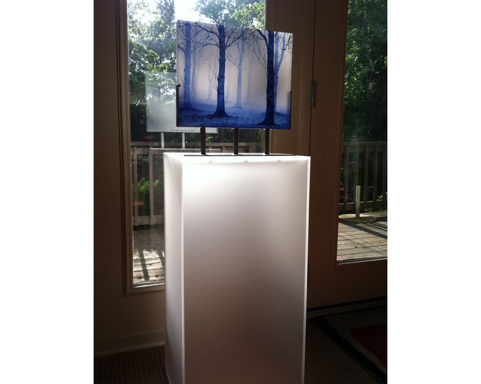 Frosted acrylic pedestal in residential environment displaying a painting/photo of blue tree