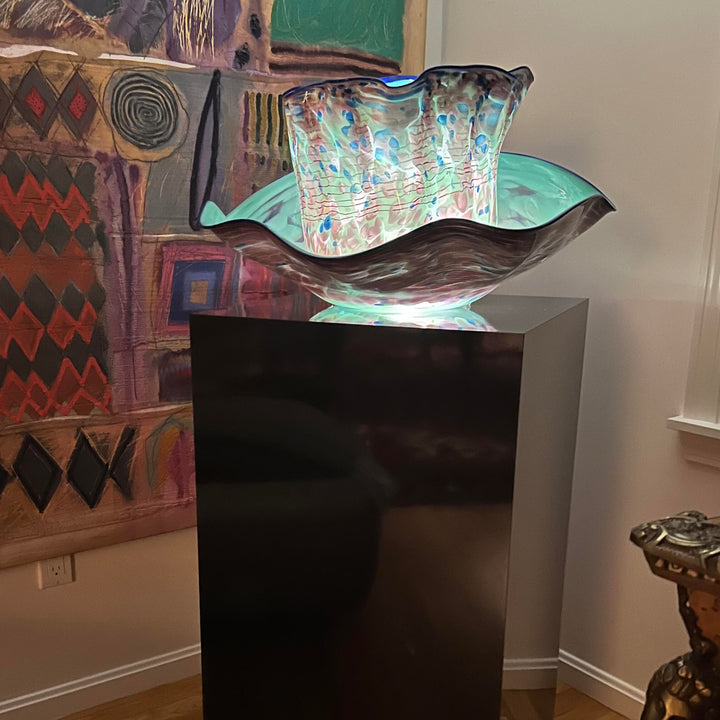black acrylic pedestal with glass artwork on it. 