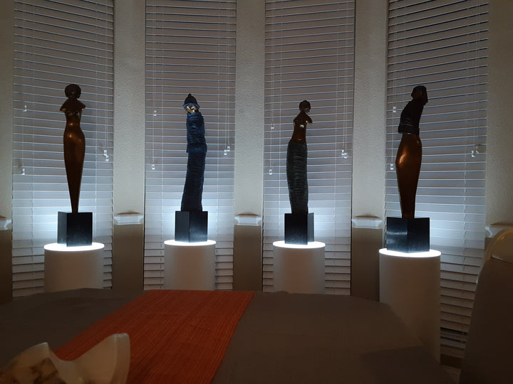 The four seasons represented as female forms displayed on white laminate cylinder pedestals with ambient lighted surfaces